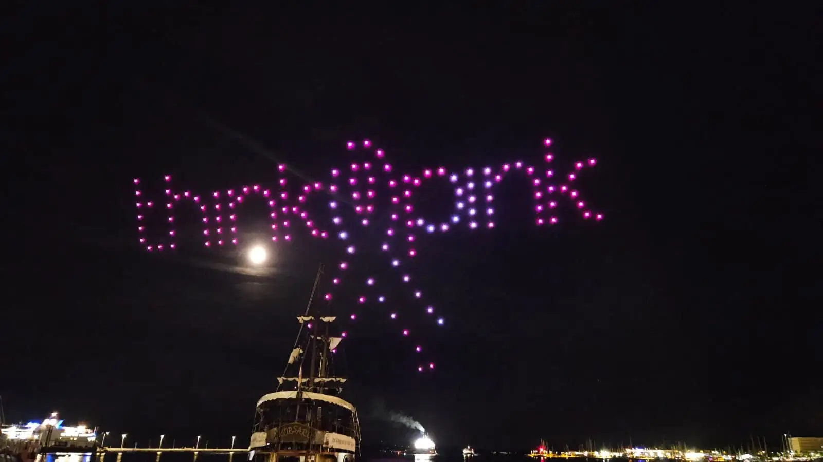 Drone light show s LightX formacijom iznad mora tijekom noćnog eventa za sprječavanje raka dojke